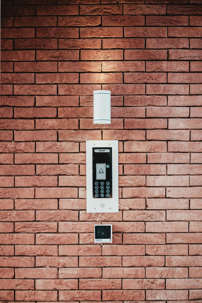 Door entry intercom panel on a red brick wall